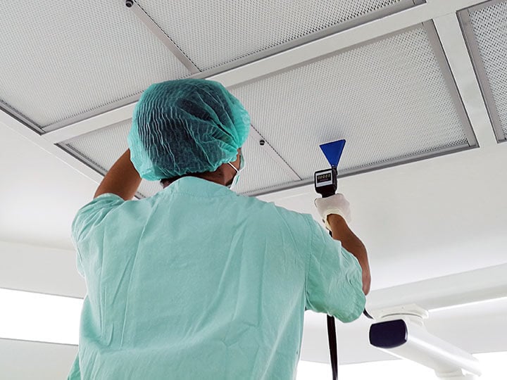 Person in protection attire performing HEPA filter installation leak test