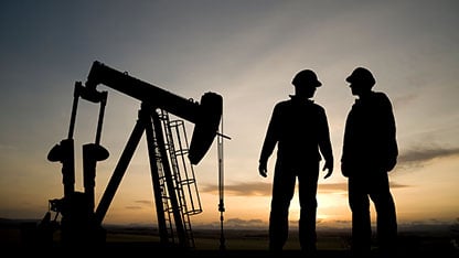 workers in silhouette at drill site