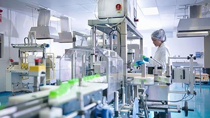 Trabalhador a inspecionar produtos na linha de produção na fábrica farmacêutica